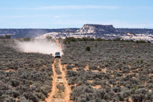 Jeep Wrangler JK driving down a dirt road with mountains in the background.