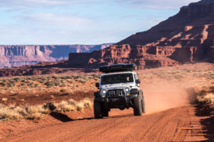 Head on shot of AEV JK 350 with high capacity coil springs driving down a dirt road