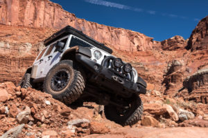 AEV Jeep Wrangler JK overcoming an obstacle on the trail.